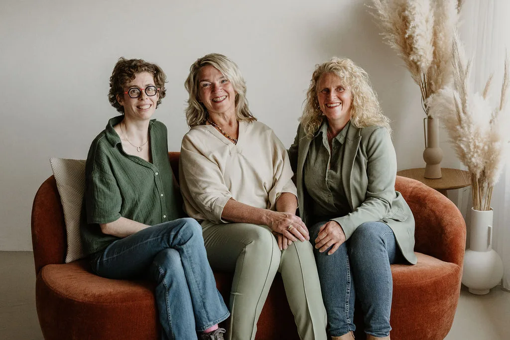 De echoscopisten Deborah, Joan en Evelien van Verloskundig Echocentrum Beverwijk-Castricum zitten lachend naast elkaar op een bank