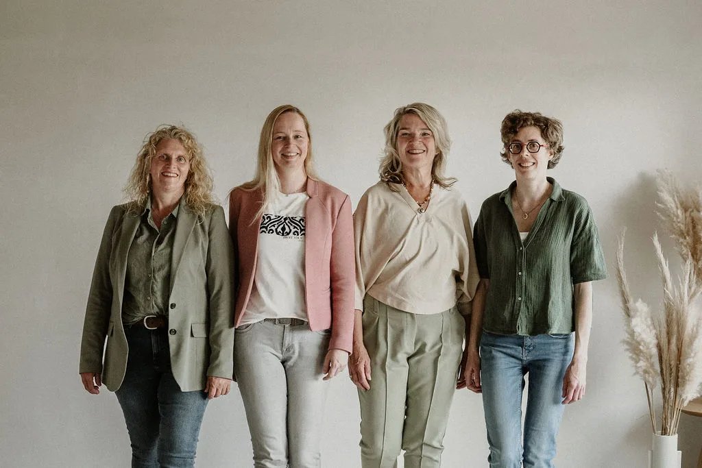 De echoscopisten Deborah, Joan en Evelien en assistente Ineke staan naast elkaar en kijken lachend in de camera